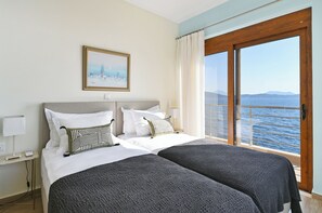 Une chambre d’hôtel avec deux lits, un tableau au mur et une vue sur la mer.