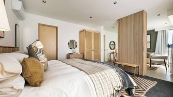 Una habitación de hotel moderna con una cama grande, un armario de madera, un escritorio y un espacio de descanso.
