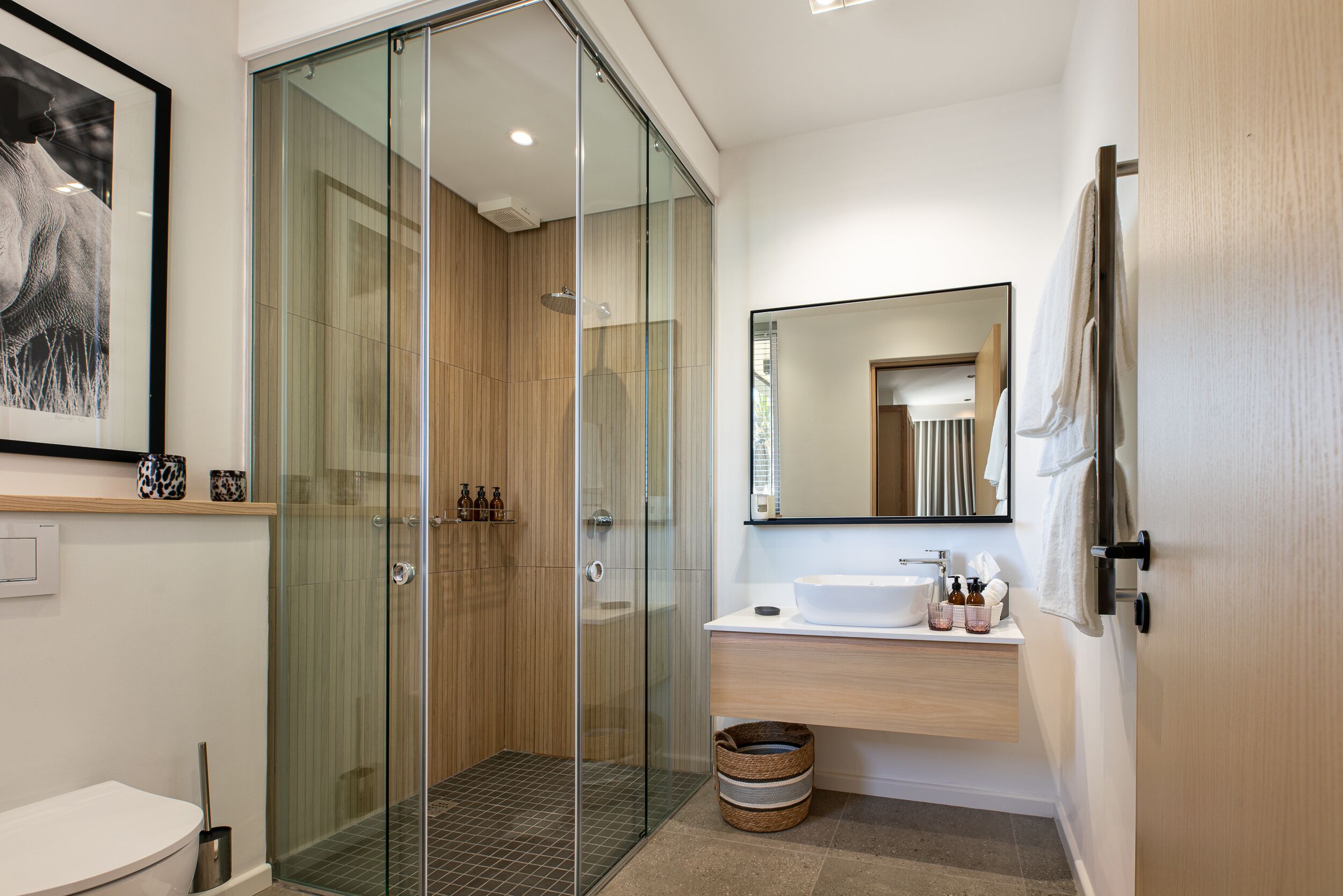 A modern bathroom with a glass-enclosed shower, a white sink, and a large mirror.