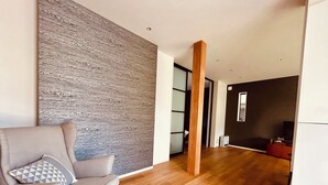 Un salon moderne avec un canapé gris, un plancher en bois et un mur à texture.