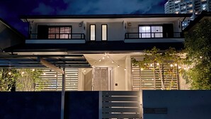 Une maison moderne à deux étages, dotée d’un porche, d’un escalier et de guirlandes lumineuses.