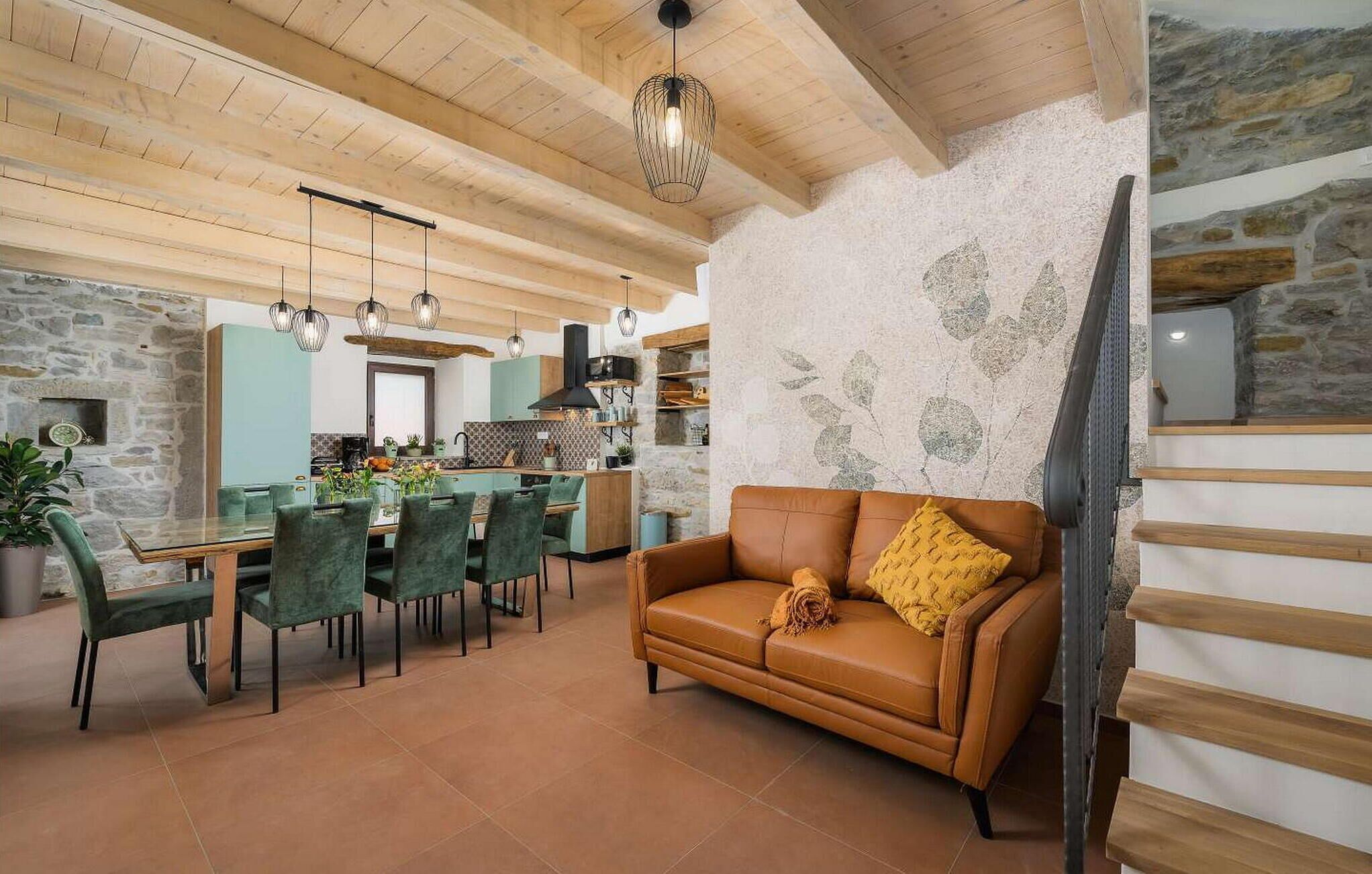 Una sala moderna con un sofá de cuero marrón, sillas verdes y una mesa de comedor.