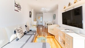 Un salon moderne avec un canapé, un téléviseur et une table basse en verre.