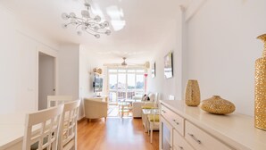 Un salon lumineux et moderne, doté d’un coin repas, de grandes fenêtres et offrant une vue sur la ville.