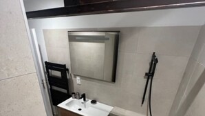 A modern bathroom with a bathtub, a sink, and a mirror. - Appartement-loft de Centre-ville (Montélimar)