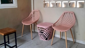 Un coin avec deux chaises roses, une petite table en bois et une poubelle.