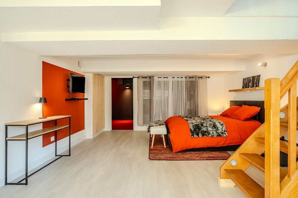 A modern bedroom with a bed, a desk, and a TV.