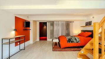 A modern bedroom with a bed, a desk, and a TV.