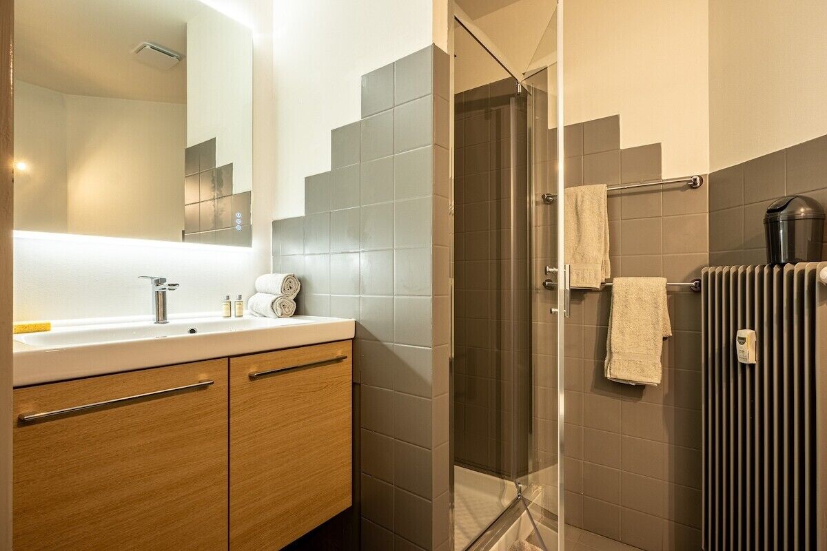 A modern bathroom with a glass shower, a sink with a mirror, and a towel rack.