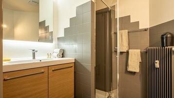 A modern bathroom with a glass shower, a sink with a mirror, and a towel rack.