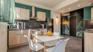 Een moderne keuken met lichte houten kastjes, een zwarte koelkast en een eettafel met witte stoelen.