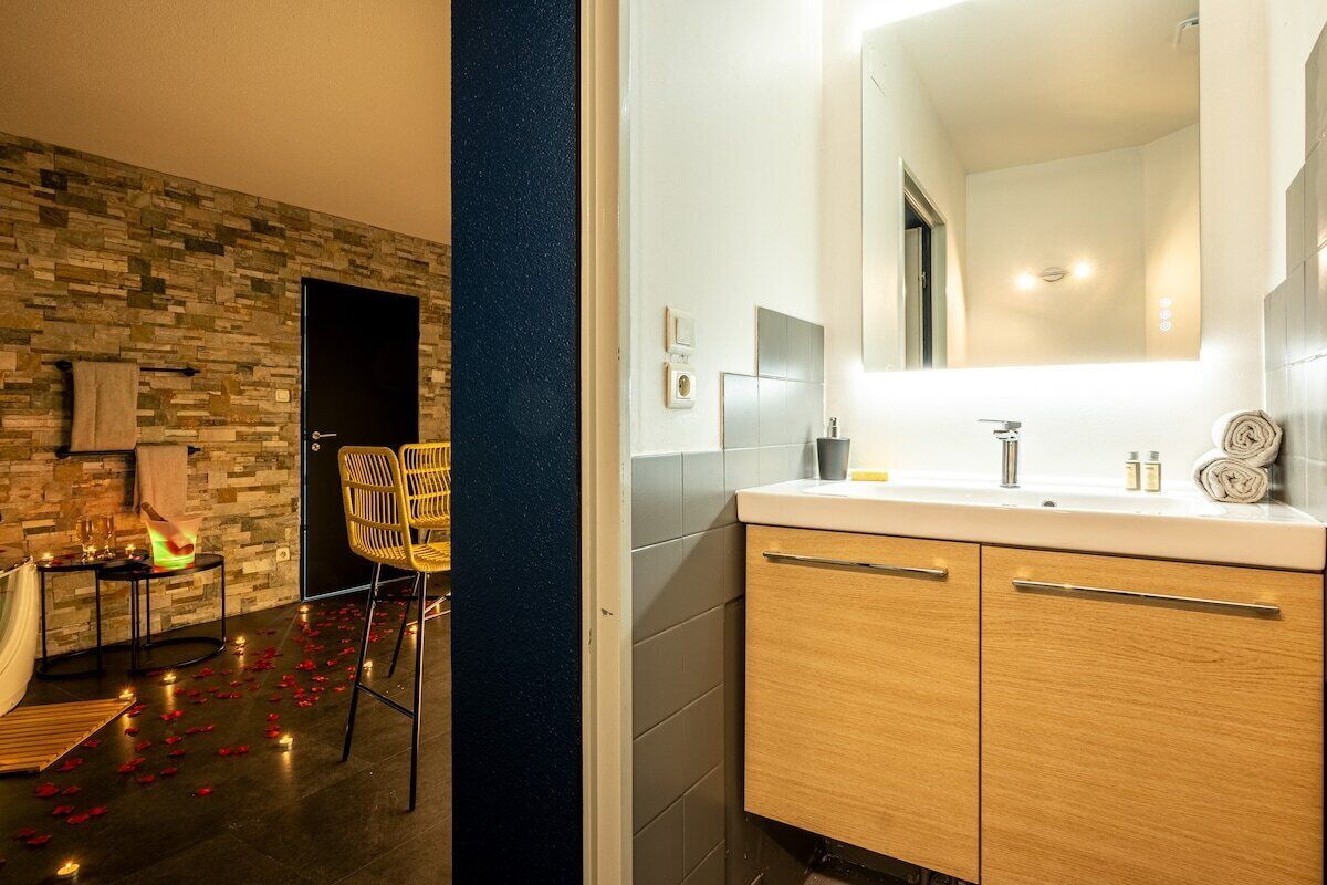 A modern bathroom with a stone wall, a large mirror, and wooden cabinets.