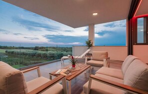 Enjoy the serene view from this balcony with a table, two chairs, and a lounge chair.
