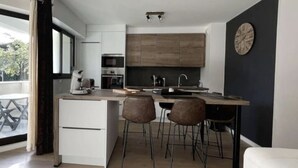 Una cocina moderna con una isla central, taburetes de bar y un ventanal grande.