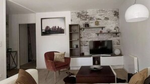 Una sala de estar moderna con un televisor de pantalla plana, un sillón rojo y un sofá blanco.