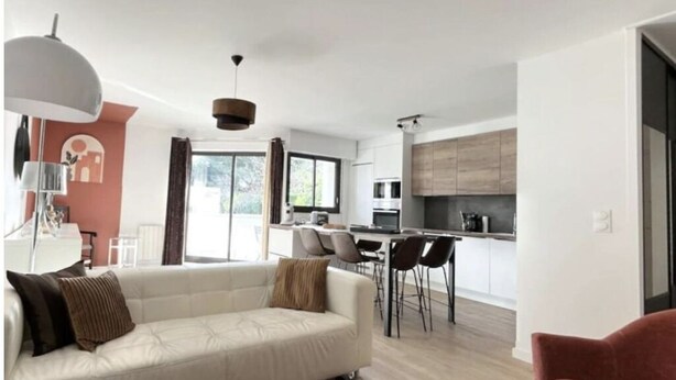 Una sala moderna con sofá, comedor y cocina.