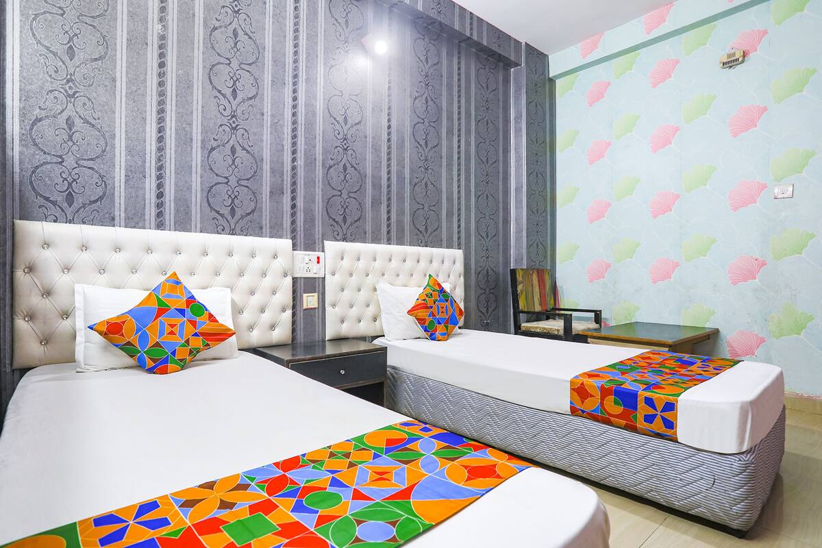 A hotel room with two beds, a nightstand, a dresser, and a small table.