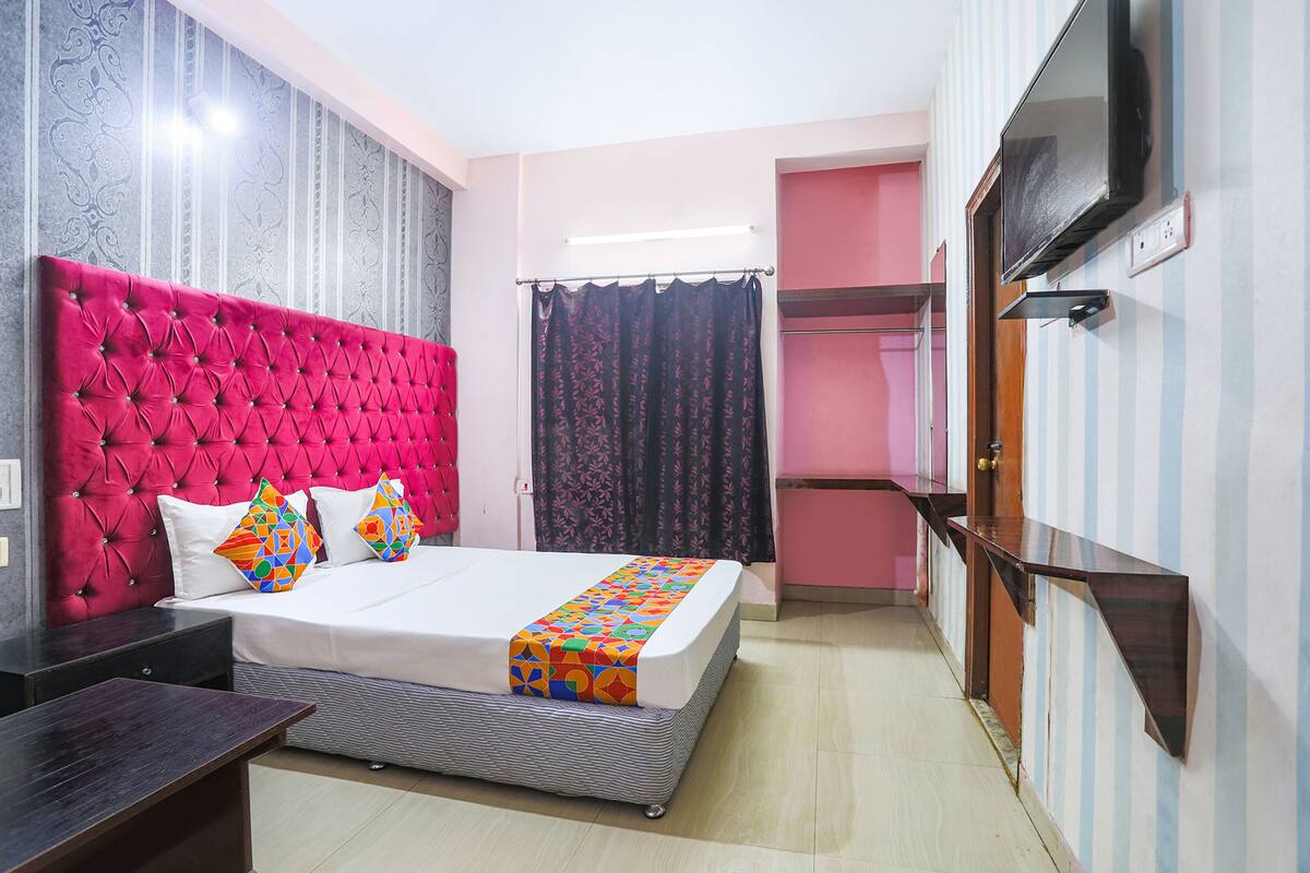 A hotel room with a large bed, a TV mounted on the wall, a bedside table, and a wardrobe.