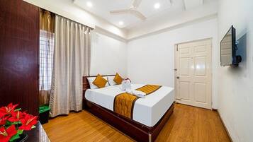 A bedroom with a wooden bed, white walls, a ceiling fan, and a door.