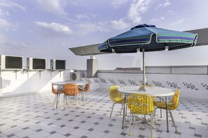 An outdoor patio with a table and chairs, an umbrella, and air conditioning units. - Fabhotel Signature Inn (Jaipur)
