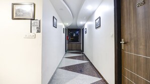Ein Hotelgang mit kariertem Boden, gerahmten Bildern an den Wänden und einer Tür mit der Aufschrift 305.