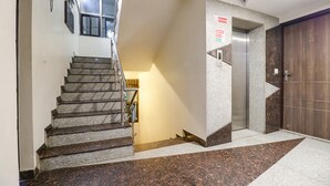 Eine Hotellobby mit einer Treppe, einem Empfangsbereich und einer Holztür mit der Nummer 301.