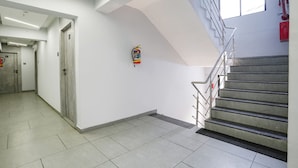 A modern interior with a staircase, a fire extinguisher, and a clean, tiled floor. - Fabhotel Aahan (Navi Mumbai)