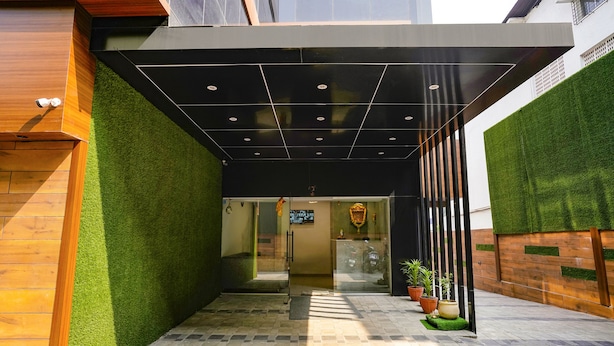 A modern building entrance with a glass door, artificial grass, and potted plants. - Fabhotel Aahan (Navi Mumbai)