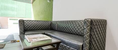 Una habitación moderna con un sofá acolchado gris, una mesa de centro de vidrio y una pared verde.