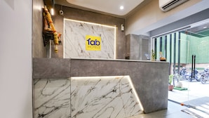 A reception desk with a marble design, a sign for 'fab hotels', and a view of the outside through large windows. - Fabhotel Aahan (Navi Mumbai)