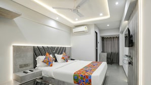 A modern hotel room with a large bed, bedside tables, a desk, and a ceiling fan. - Fabhotel Aahan (Navi Mumbai)
