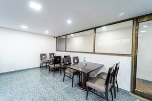 A conference room with a large table and chairs, a water bottle on the table, and a glass partition wall. - Treebo Seven Days, Mahabaleshwar (Mahabaleshwar)