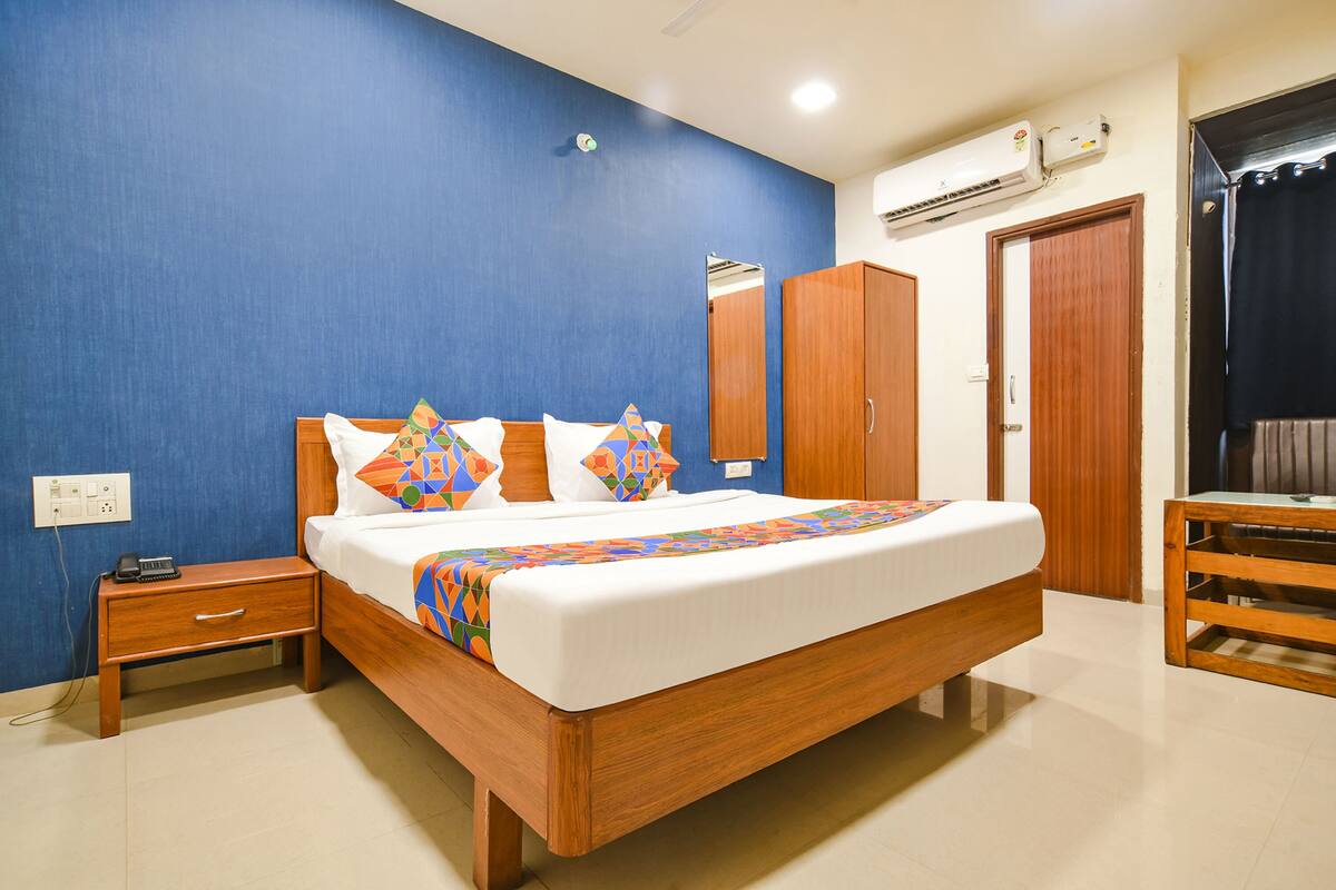 A bedroom with a bed, nightstand, wardrobe, and a mirror.
