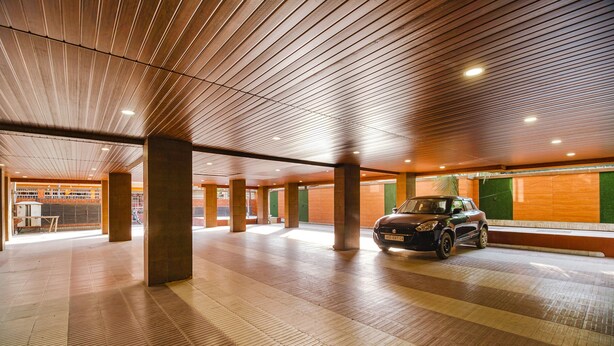 A spacious indoor parking area with a wooden ceiling and tiled floor. - Fabhotel Apple Tree (Guwahati)