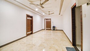 A hallway with two wooden doors, a ceiling fan, and a small table with a device. - Fabhotel Apple Tree (Guwahati)