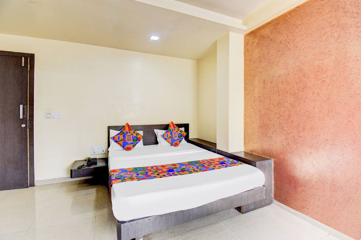 A hotel room with a bed, a nightstand, and a door.
