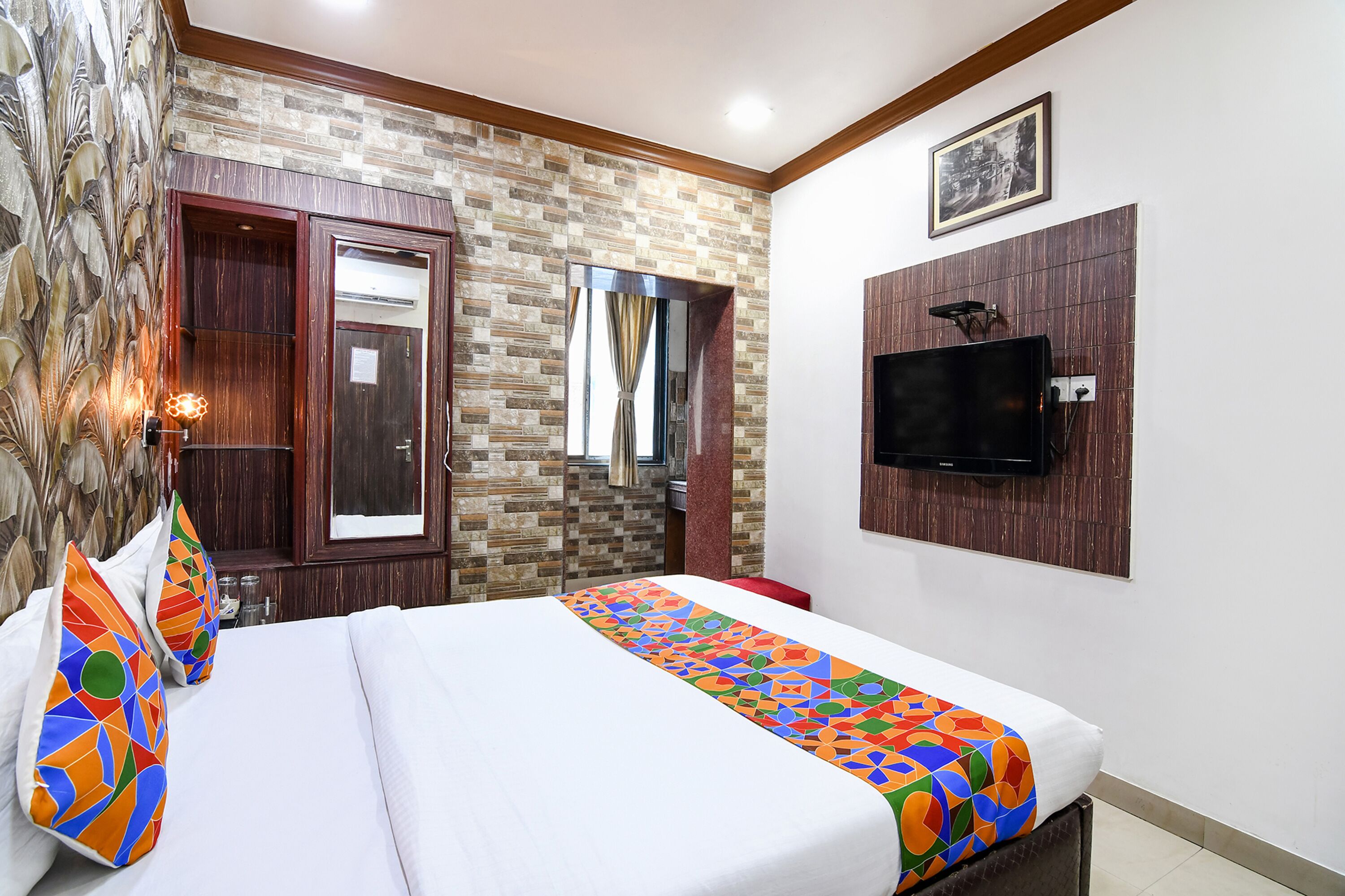 A hotel room with a bed, a TV mounted on the wall, and a patterned wall.