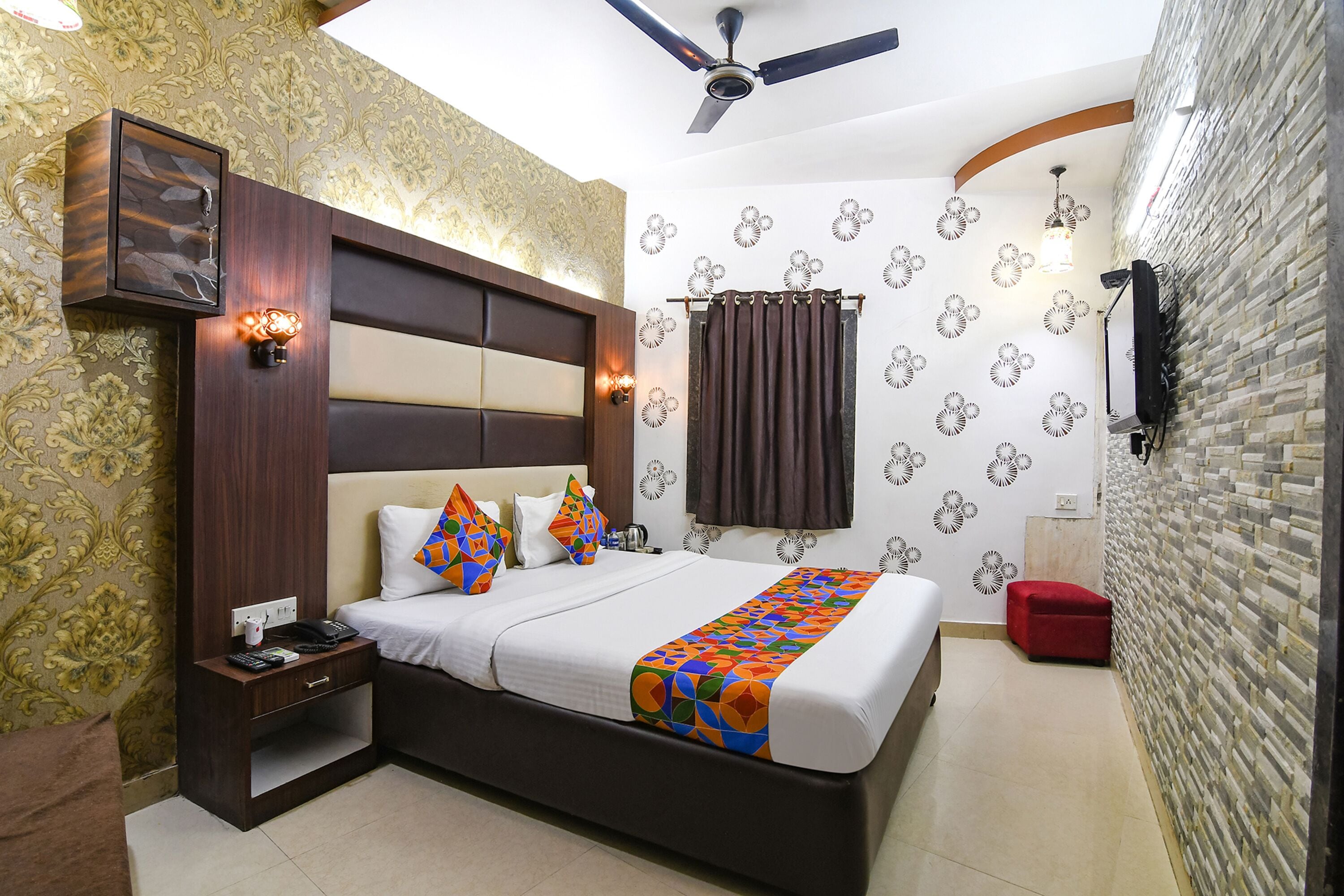 Ein Hotelzimmer mit Bett, Nachttisch und Hocker in Rot.