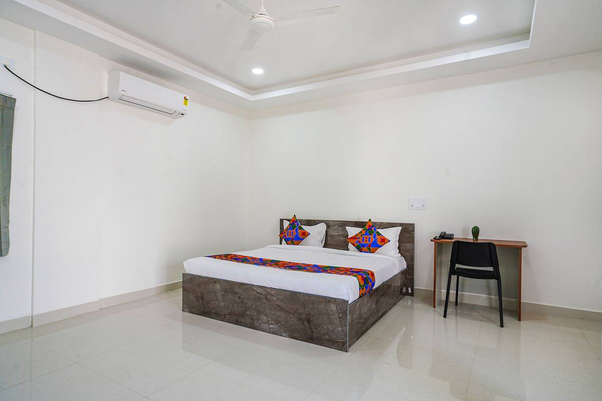 A bedroom with a bed, a desk, and a chair.