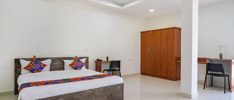 A bedroom with a bed, a desk, and a wardrobe.
