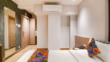 A hotel room with a bed, a nightstand, a phone, and an air conditioning unit.