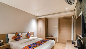 Una camera d'albergo con un letto, comodino, armadio e uno specchio.