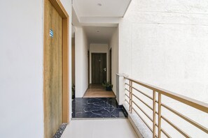 Un pasillo con puerta de madera, una planta en maceta y suelo de mármol.