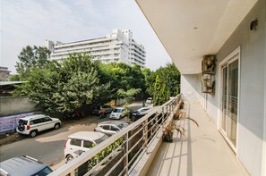 Un balcon donnant sur une rangée de voitures garées et sur un immeuble en arrière-plan.