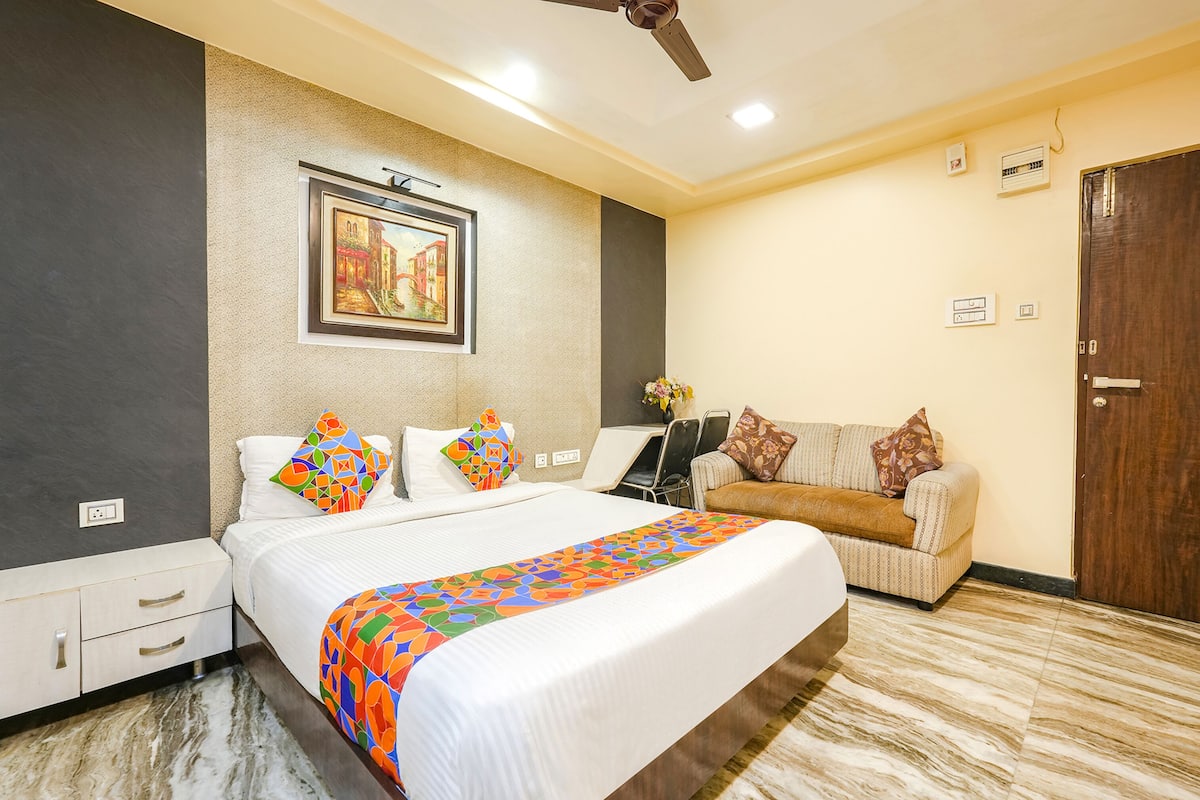Una habitación de hotel con cama, sofá, escritorio y ventilador de techo.