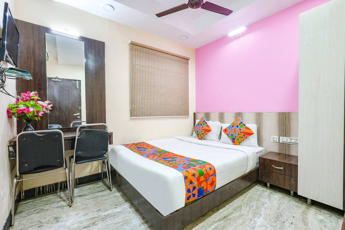 Una habitación de hotel con cama, mesita de noche, escritorio, sillas y espejo.