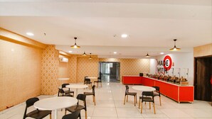 A restaurant with round tables and chairs, a red counter with food items, and patterned walls. - Fabhotel Moro Rohini Sector 11 (New Delhi)