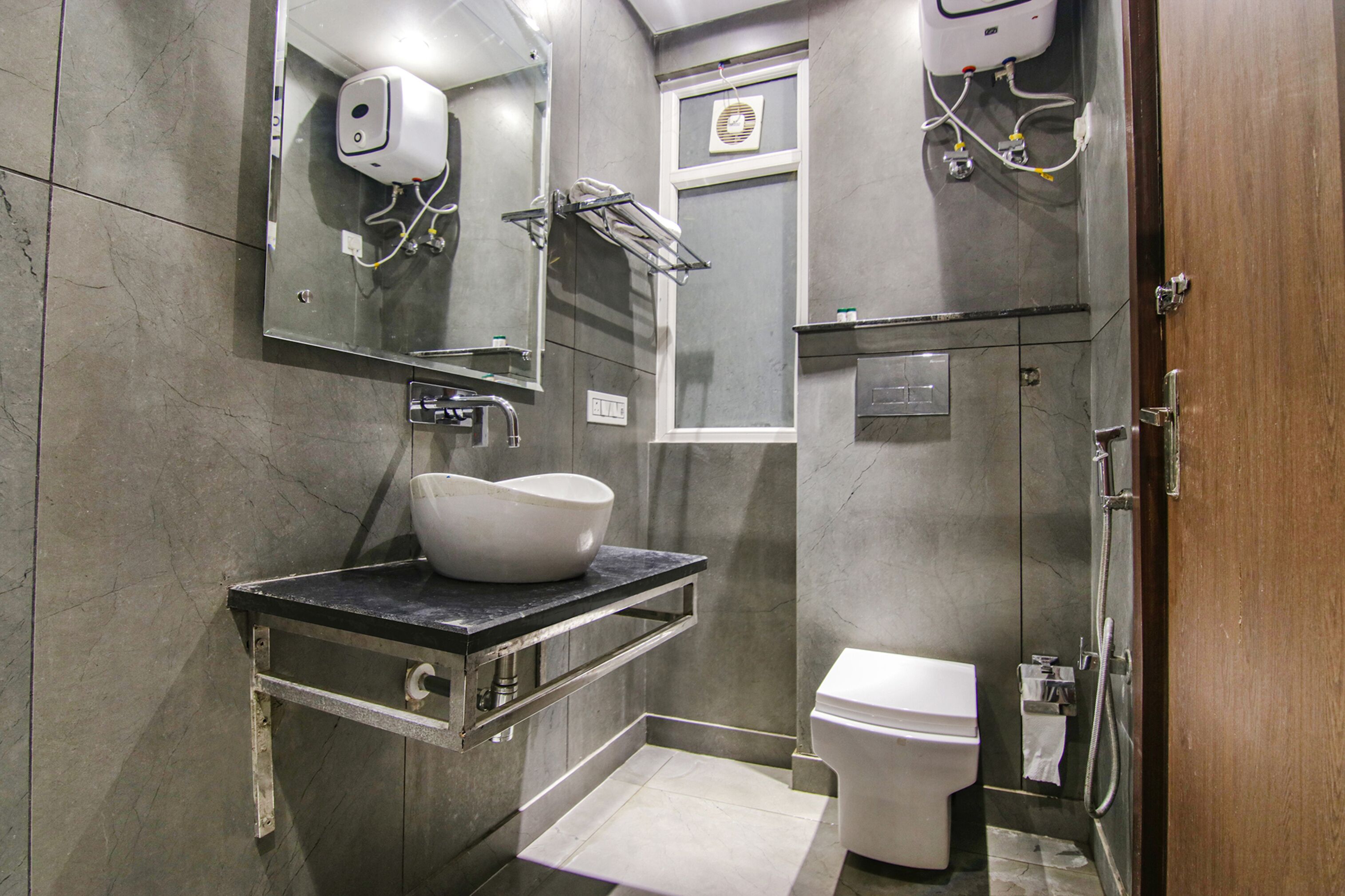 A modern bathroom with a marble sink, a handheld showerhead, and a toilet.