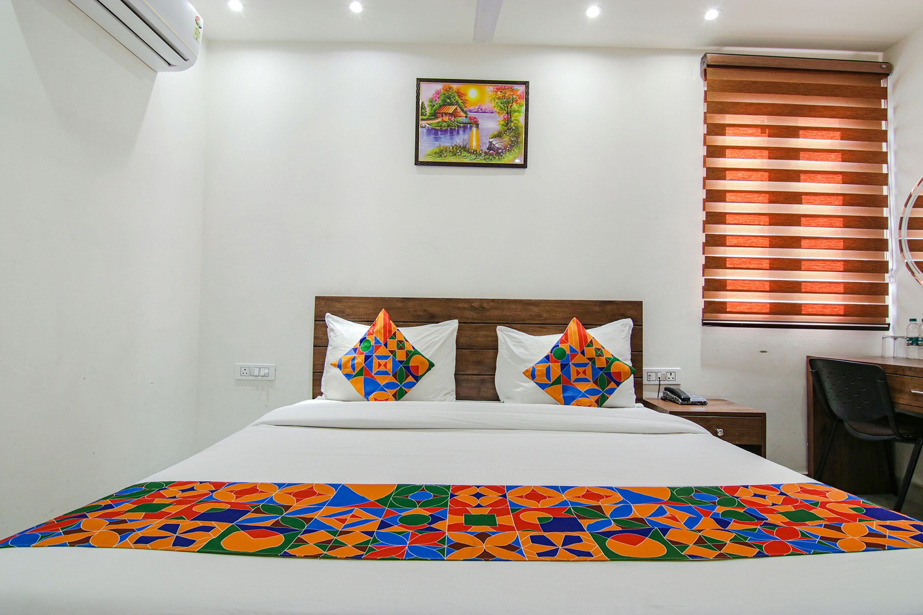 Une chambre d’hôtel avec un lit, un bureau et une fenêtre équipée de stores.