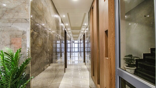 A corridor with marble walls, wooden paneling, and a potted plant. - Fabhotel Moro Rohini Sector 4 (New Delhi)